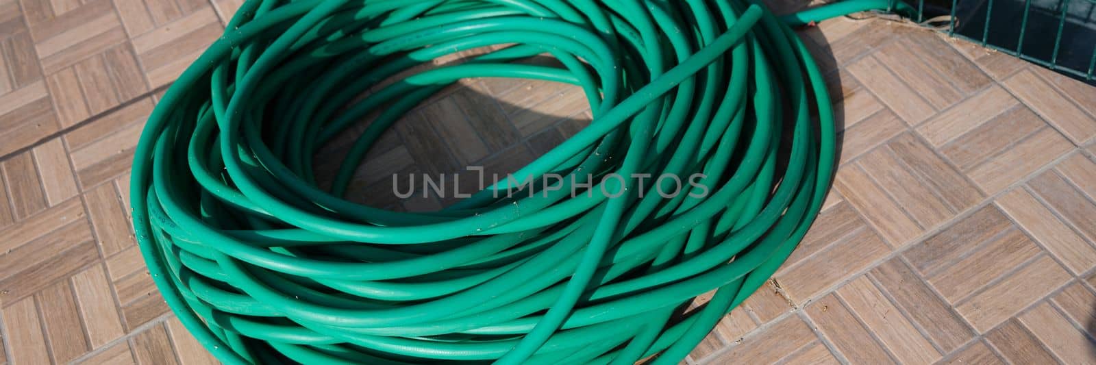 Green twisted garden hose in garden. Watering system and choosing a quality garden hose