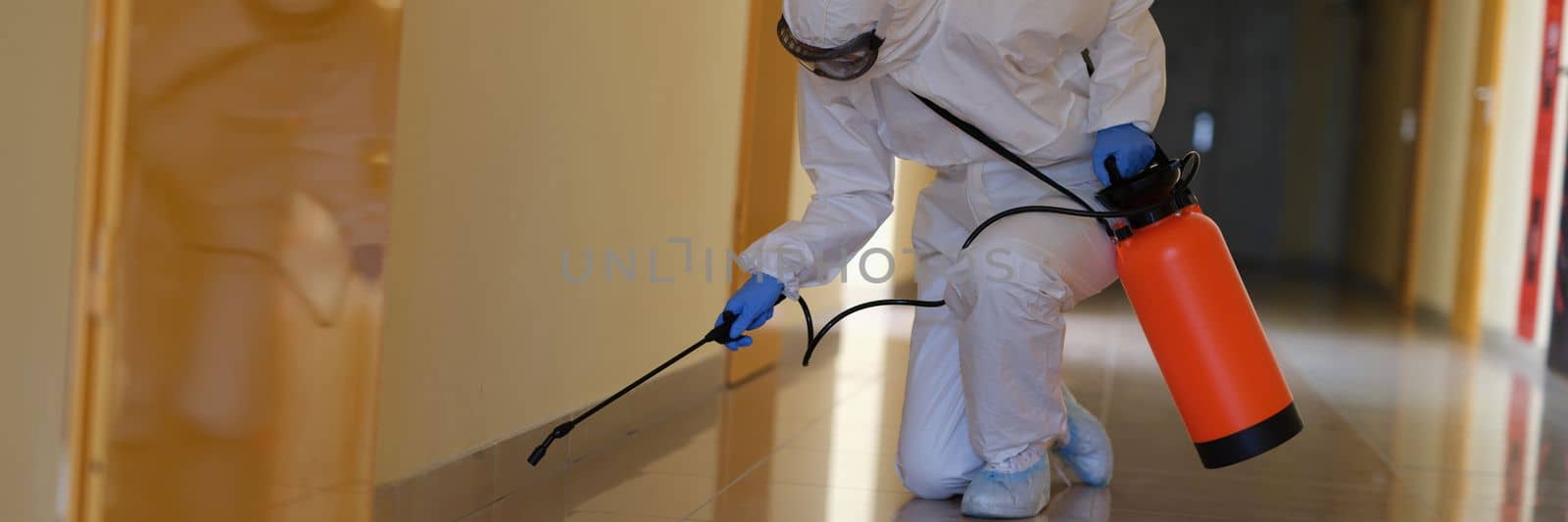 Person in hazmats are cleaned in corridor of hospital or public office Building. Coronavirus disinfection concept and door treatment