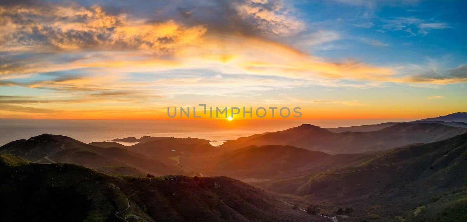 Sunset over ocean with rugged mountain coast and beautiful color in clouds. High quality photo