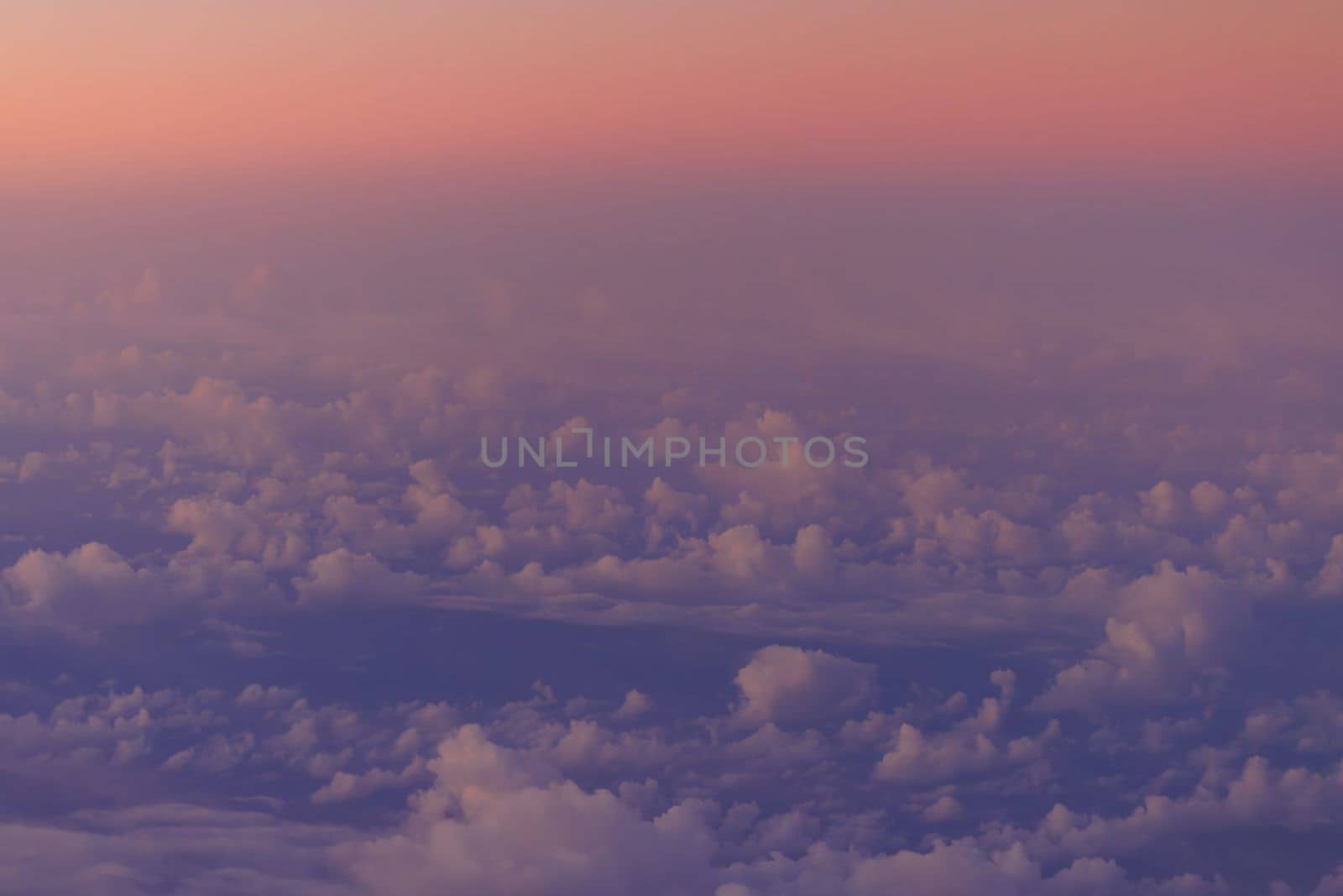 Pink glow on horizon over clouds and blue ocean at sunrise by Osaze