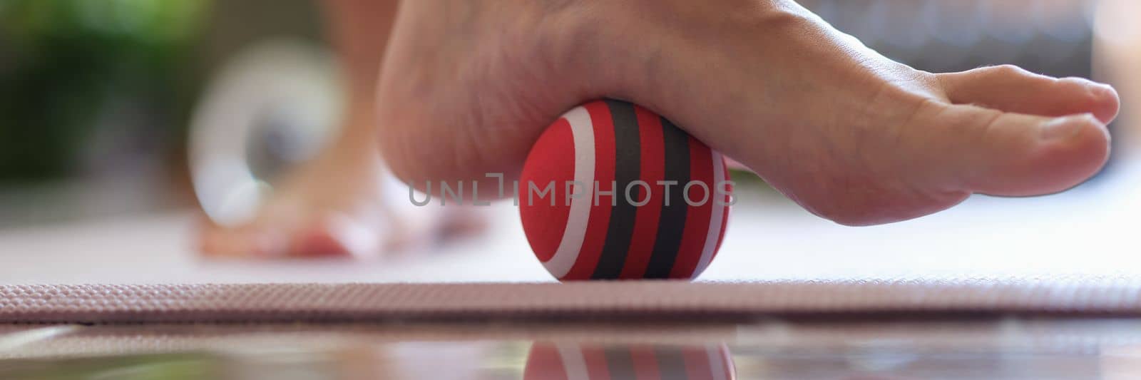 Person rolls ball on foot at home closeup. Foot massage ball concept