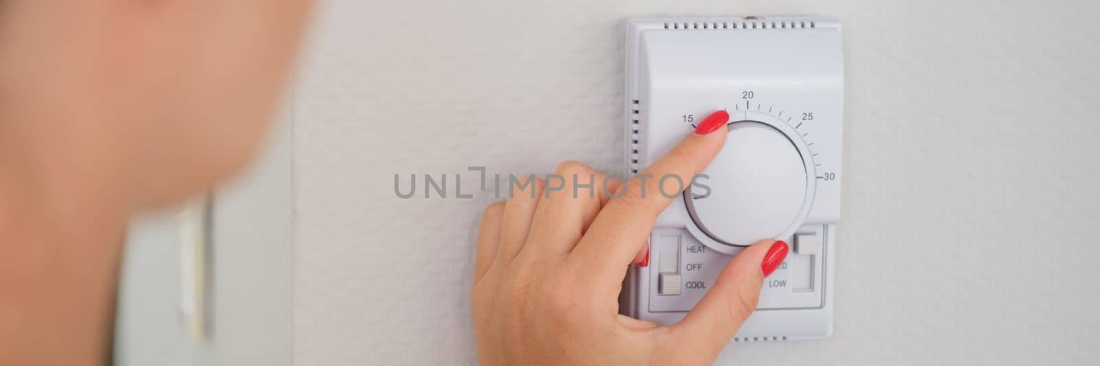Hand adjusts button of the control unit of heating and cooling system of house closeup. Home or office climate control