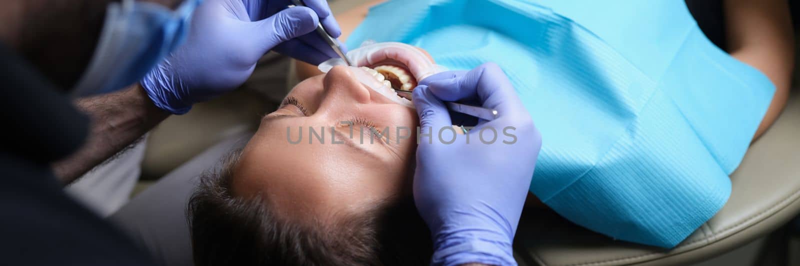 Dentist treats teeth with caries to female patient in dental clinic. Care and treatment of teeth concept