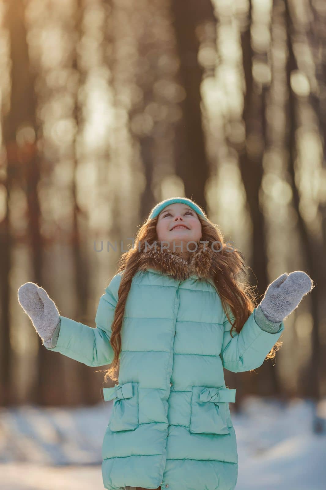 girl in a turquoise squat and a hat in a winter forest, shot vertically