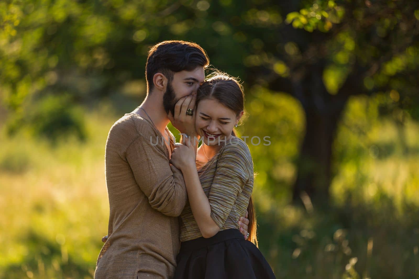 man tells in his ear the secret of his girlfriend walking in the park