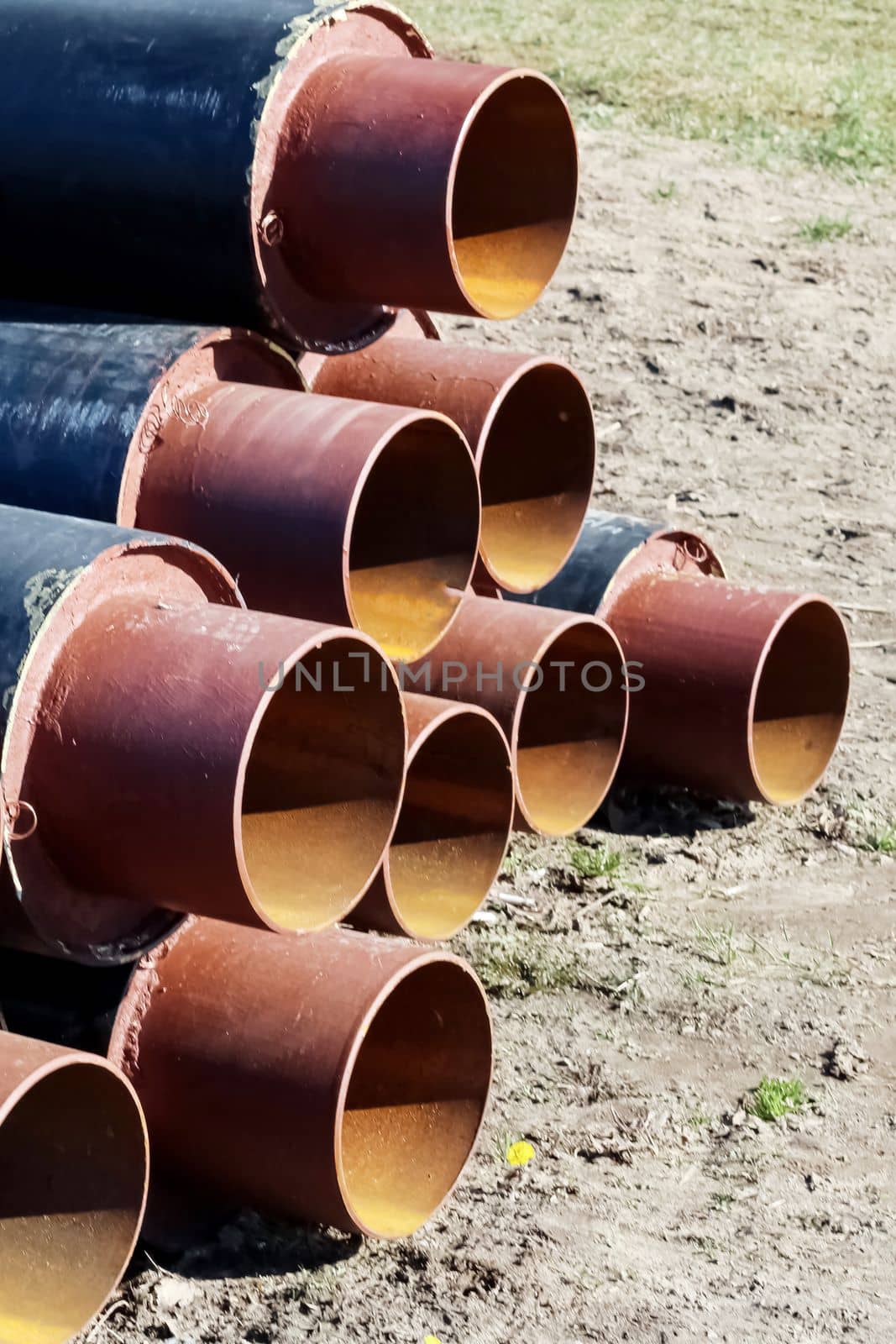 Black metal pipes for water pipes folded on the grass close up