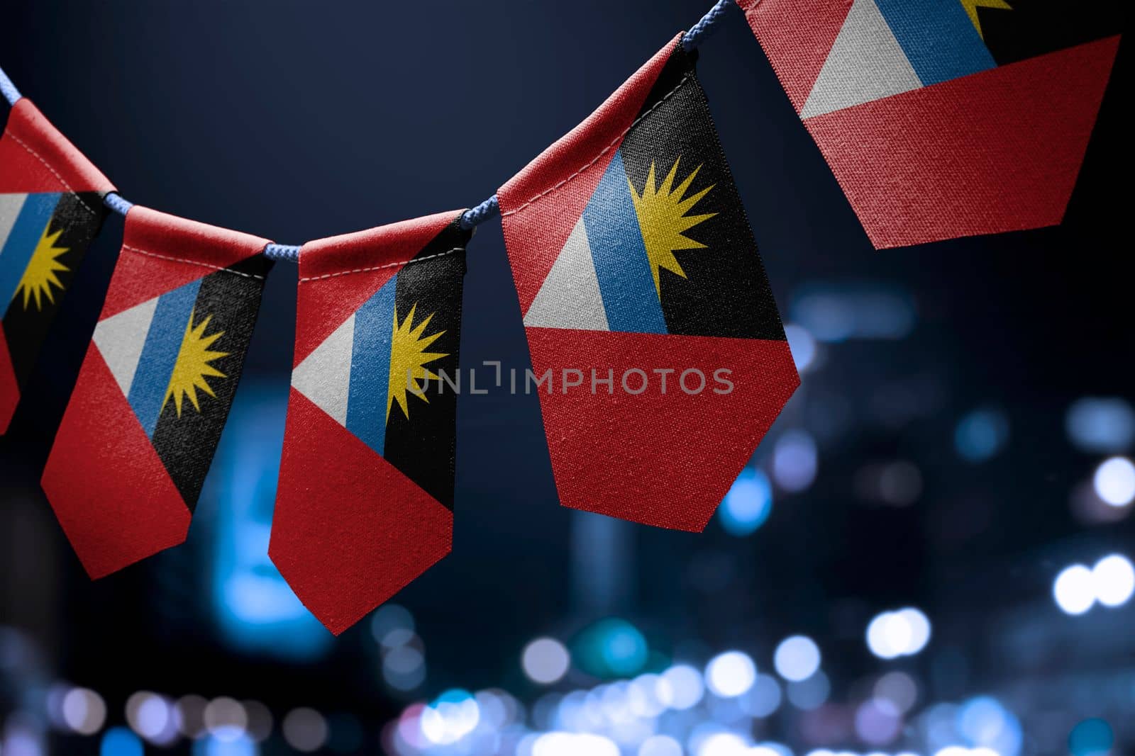 A garland of Antigua and Barbuda national flags on an abstract blurred background.