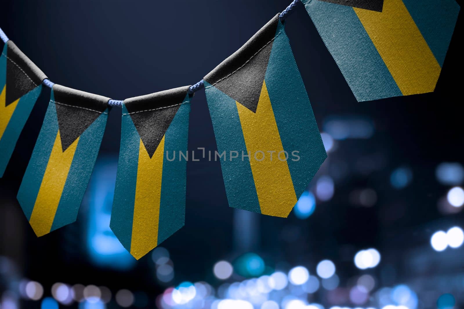 A garland of Bahamas national flags on an abstract blurred background by butenkow