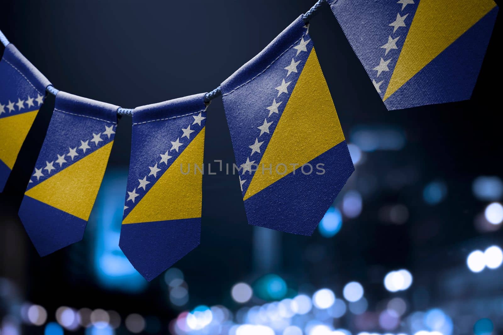 A garland of Bosnia and Herzegovina national flags on an abstract blurred background.