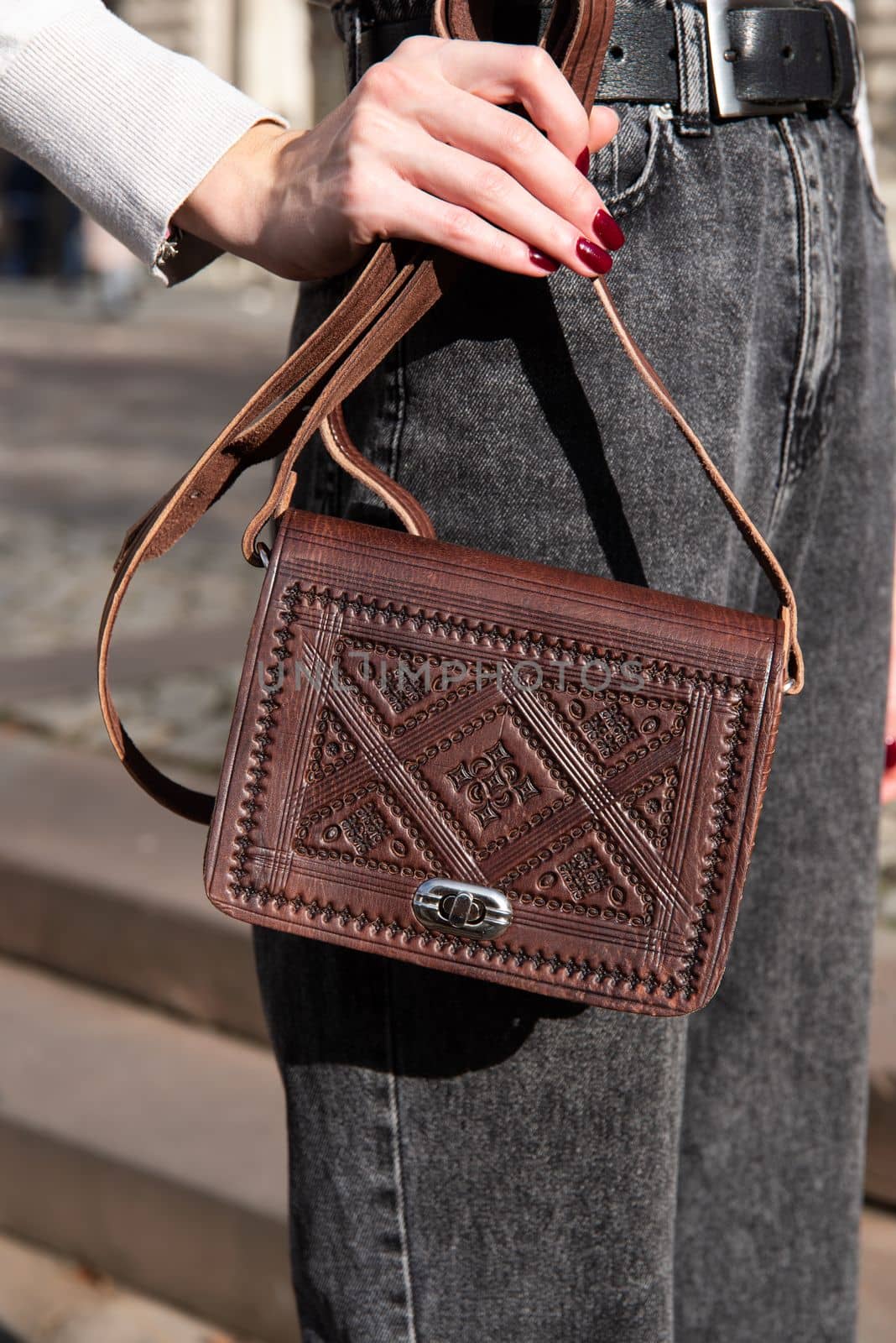 small brown women's leather bag with a carved pattern. street photo