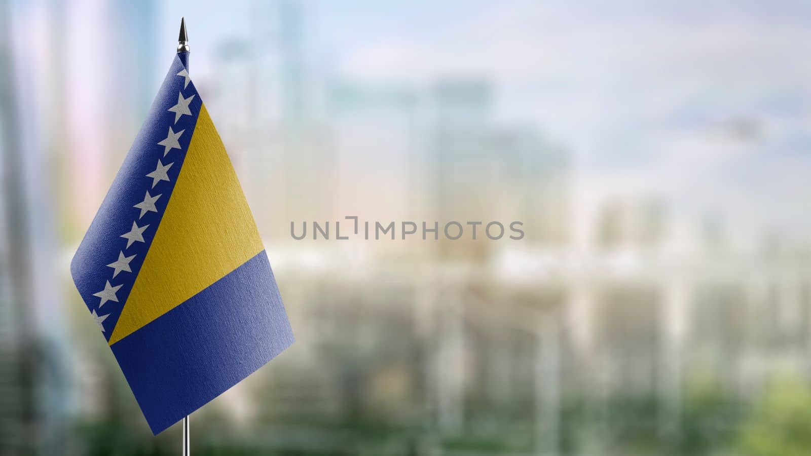 Small flags of the Bosnia and Herzegovina on an abstract blurry background.