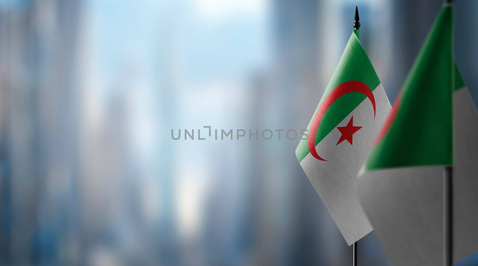 Small flags of the Algeria on an abstract blurry background.
