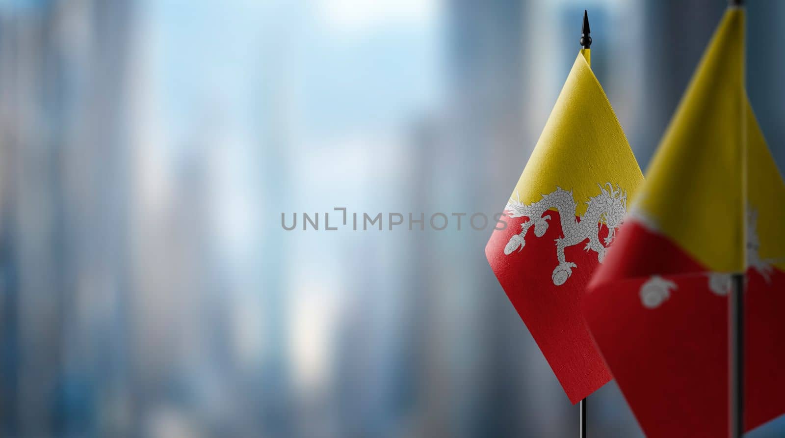 Small flags of the Bhutan on an abstract blurry background.