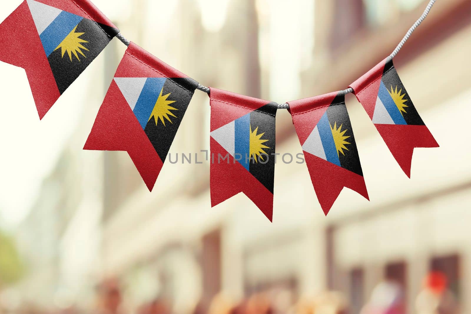 A garland of Antigua and Barbuda national flags on an abstract blurred background by butenkow