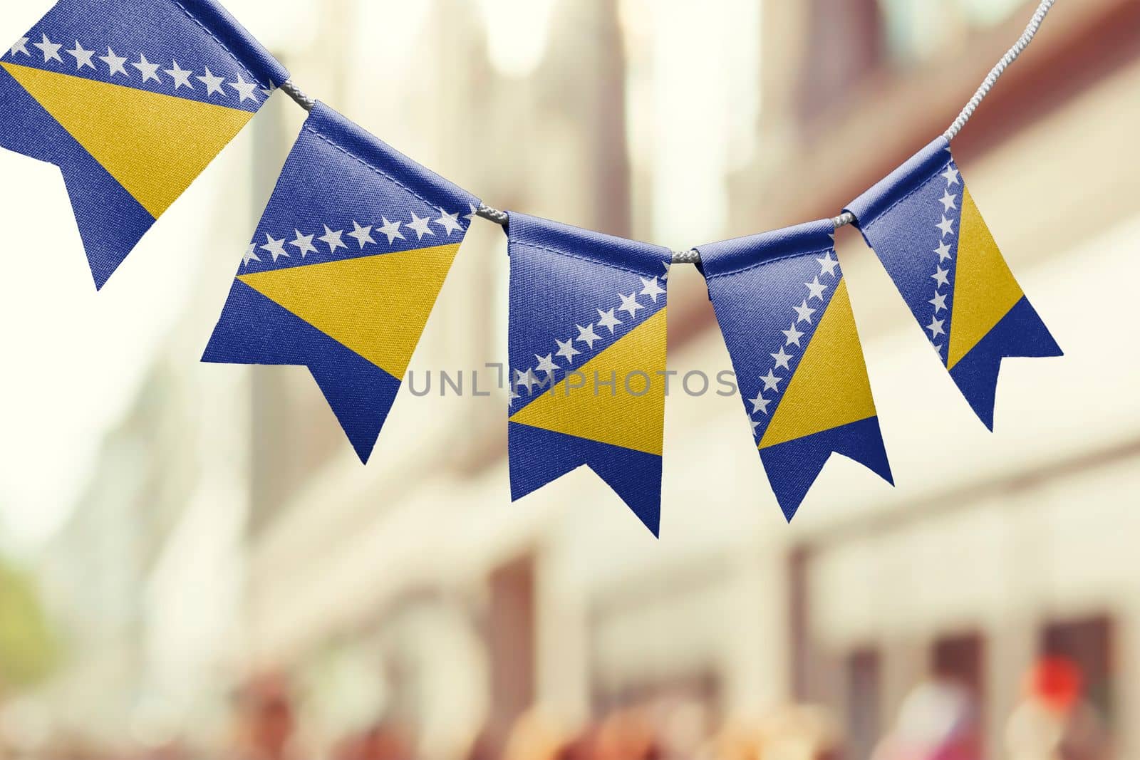 A garland of Bosnia and Herzegovina national flags on an abstract blurred background.