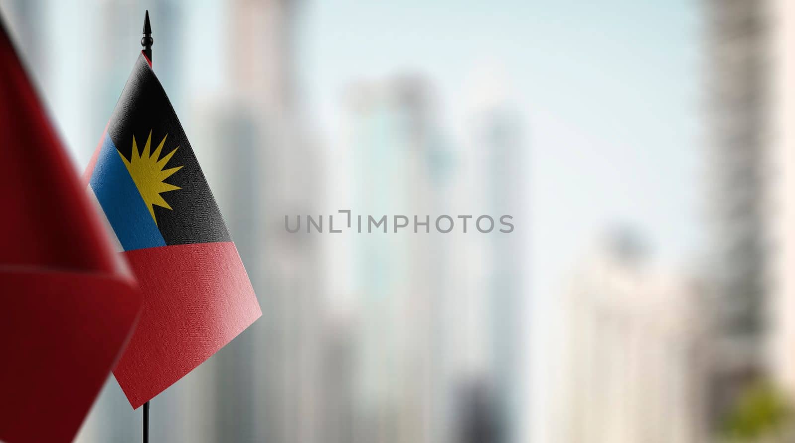 Small flags of the Antigua and Barbuda on an abstract blurry background.