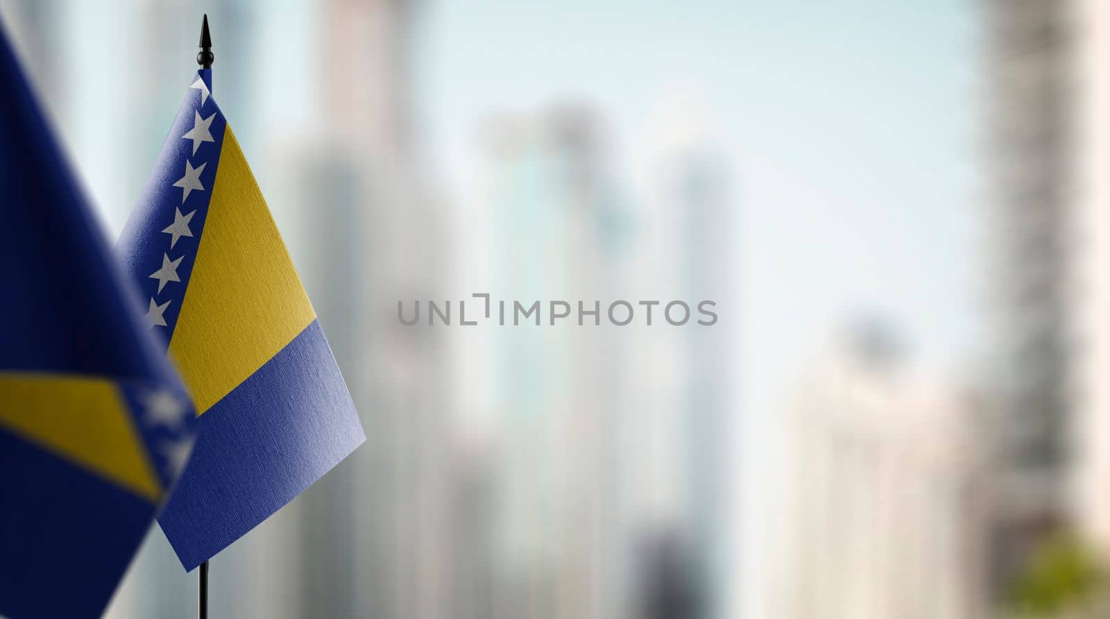 Small flags of the Bosnia and Herzegovina on an abstract blurry background.