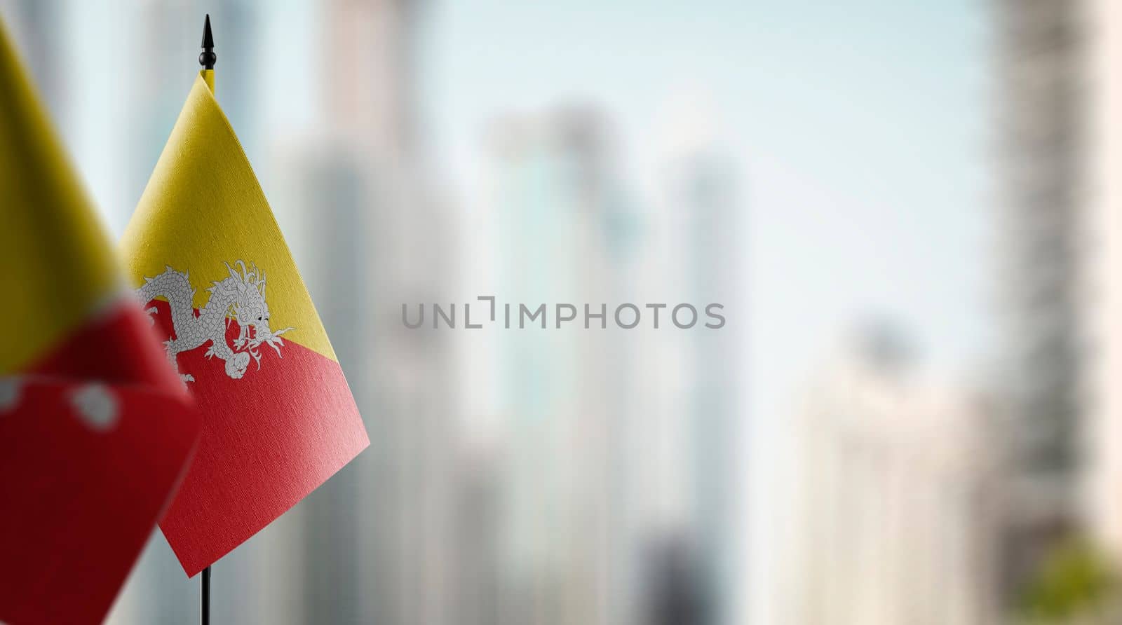 Small flags of the Bhutan on an abstract blurry background.