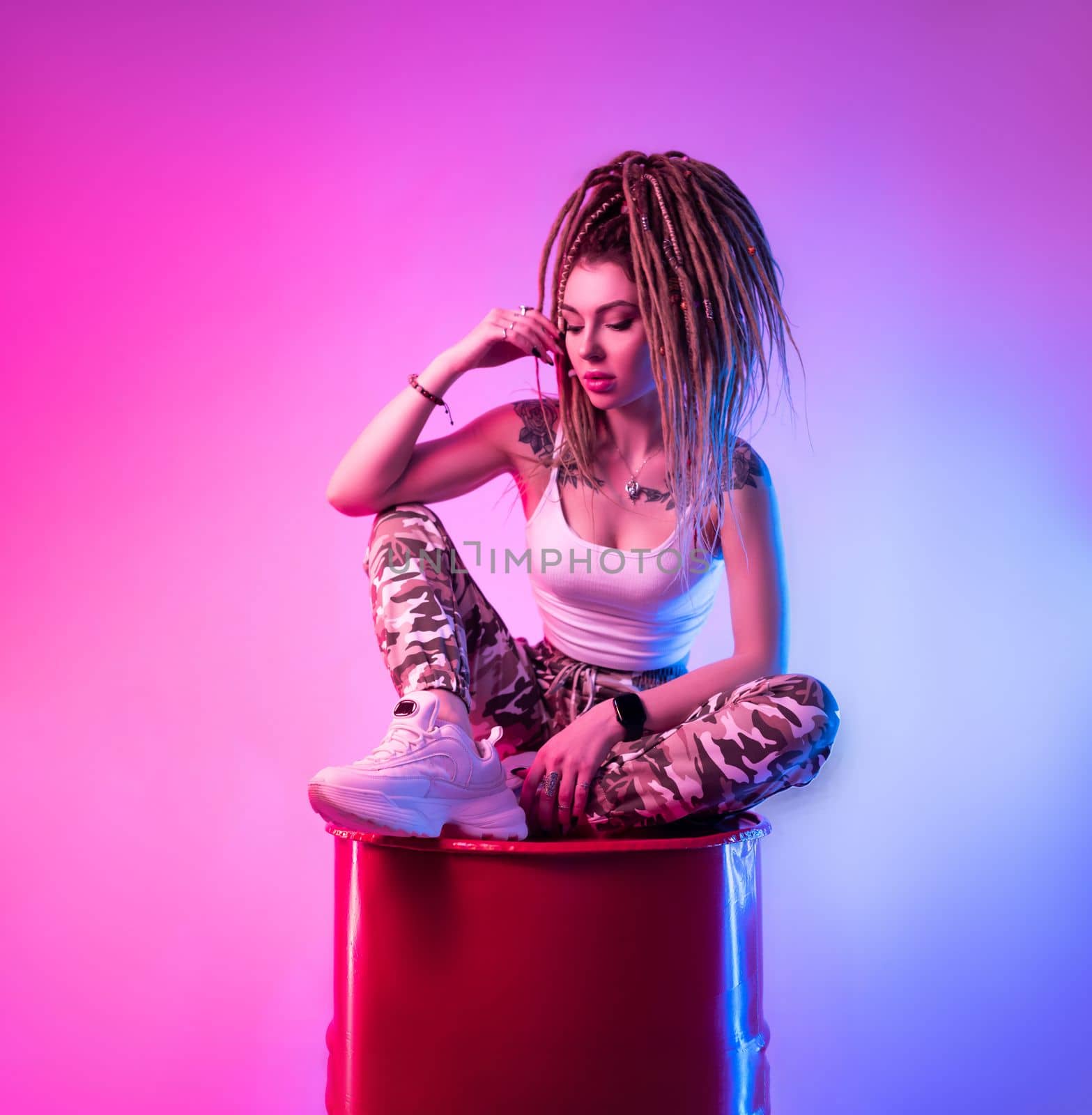 sexy girl with braided dreadlocks on her head in neon light on light background copy paste