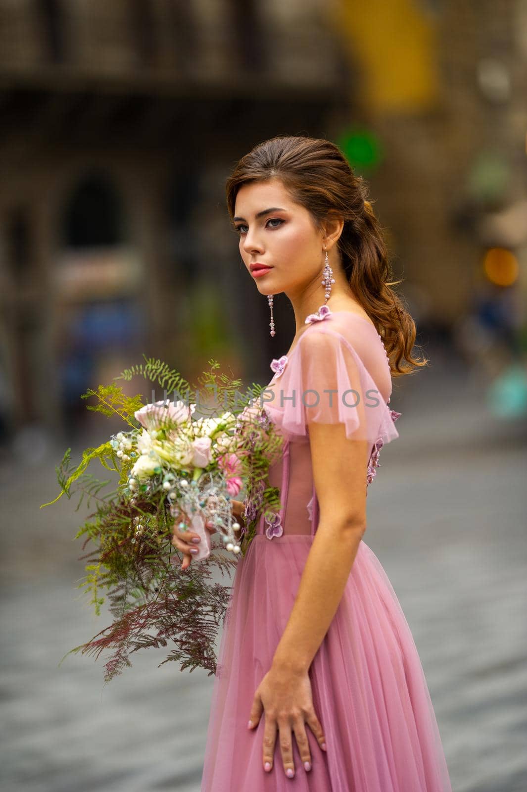 A bride in a pink dress with a bouquet stands in the center of the Old City of Florence in Italy.
