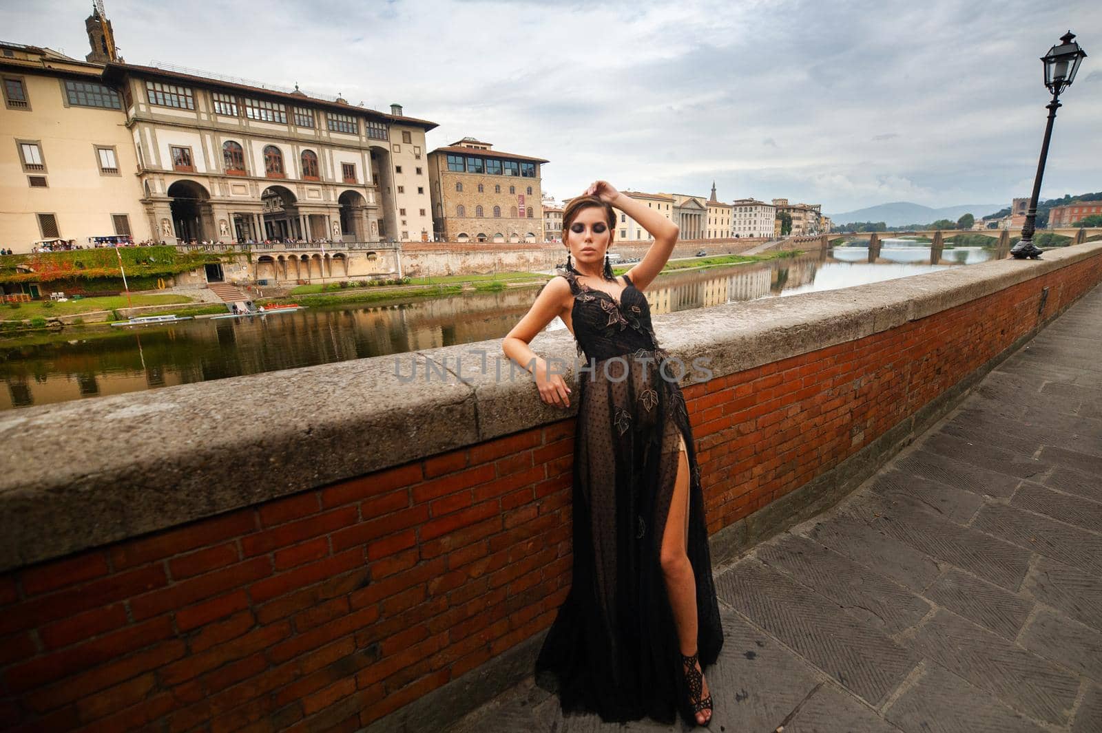 Beautiful stylish bride in a black dress stands on the embankment in Florence, Italy.