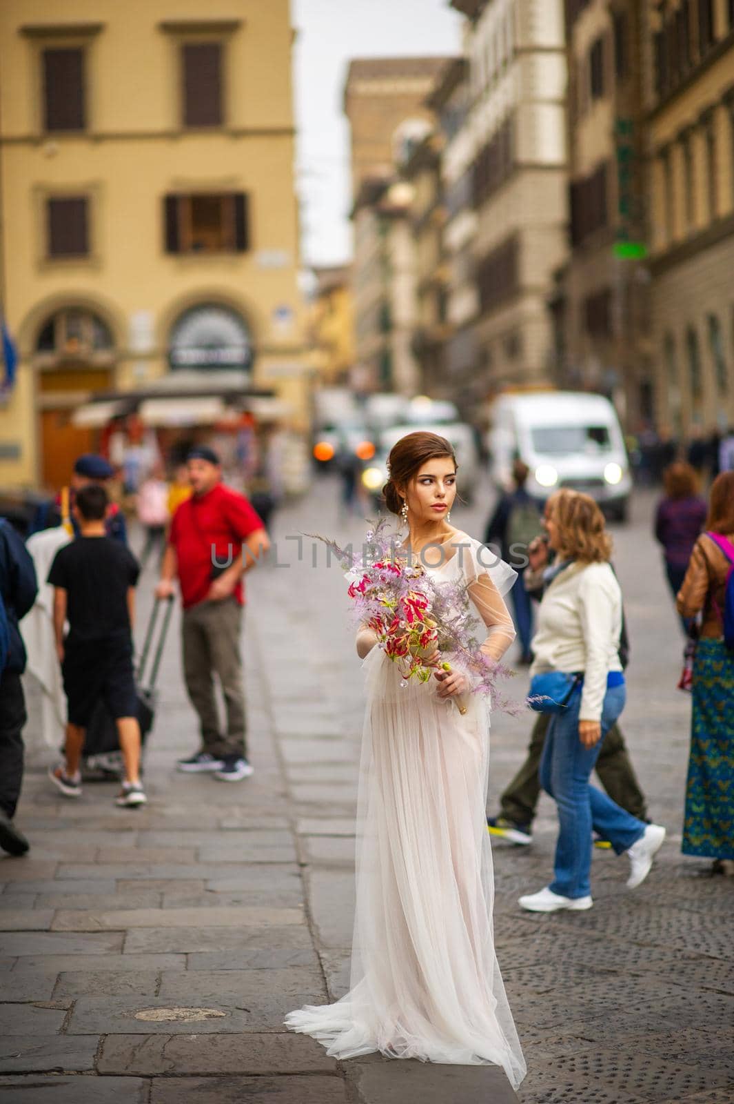 a bride in a wedding dress with a Venetian mask in her hands in Florence.Italy by Lobachad