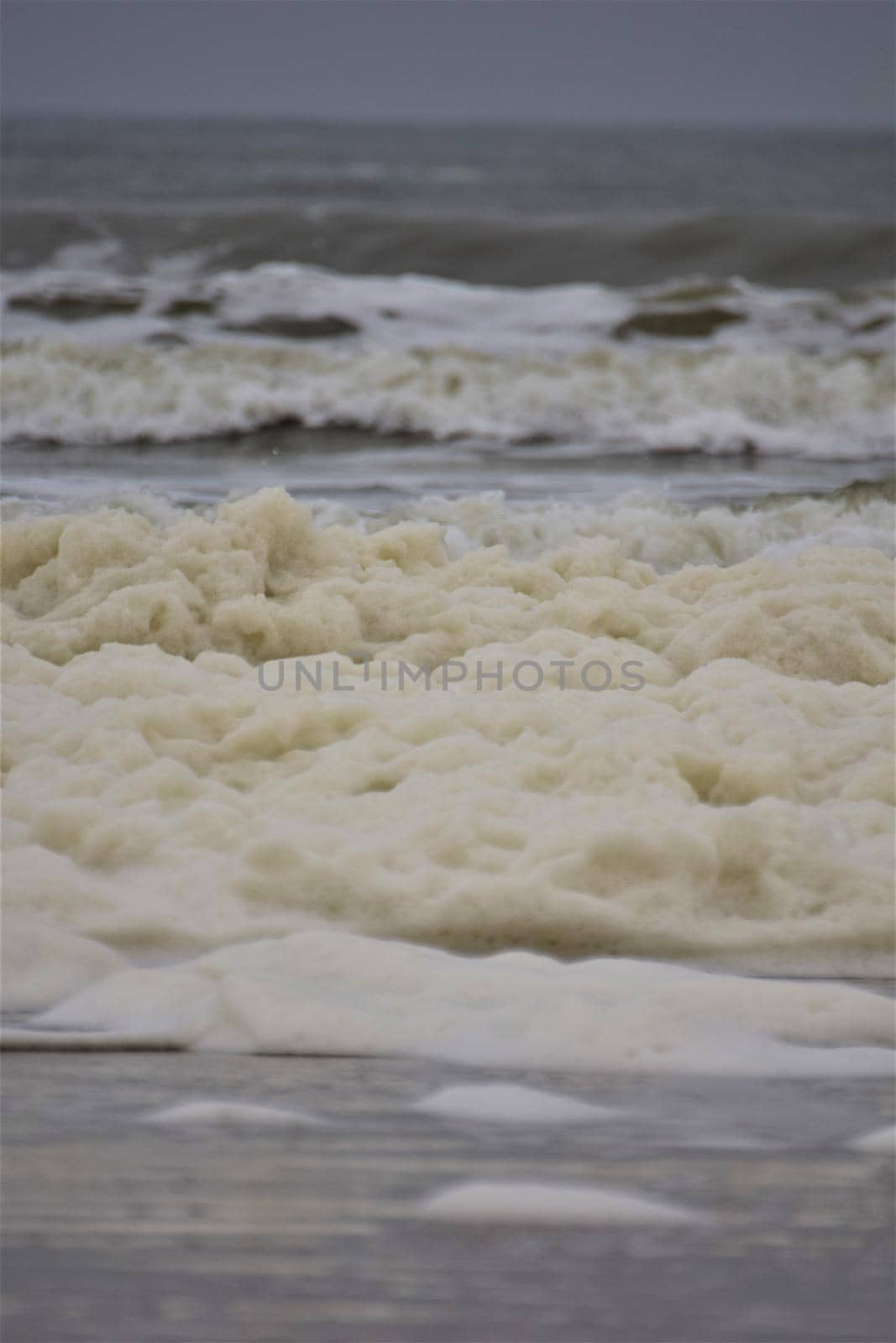 Waves and sea foam on a beach of the North Sea on a cloudy day by Luise123