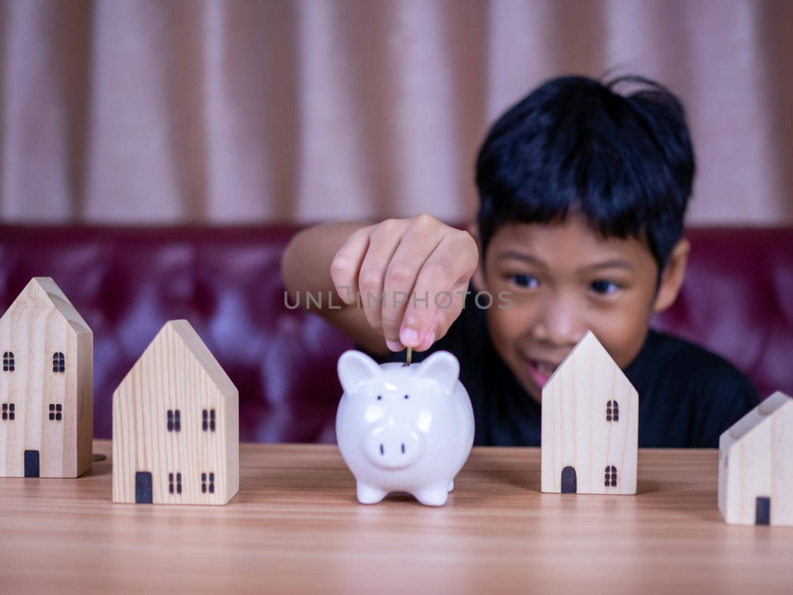 Boy saving money in a white pig piggy bank.Saving concept. Saving for the future. by Unimages2527