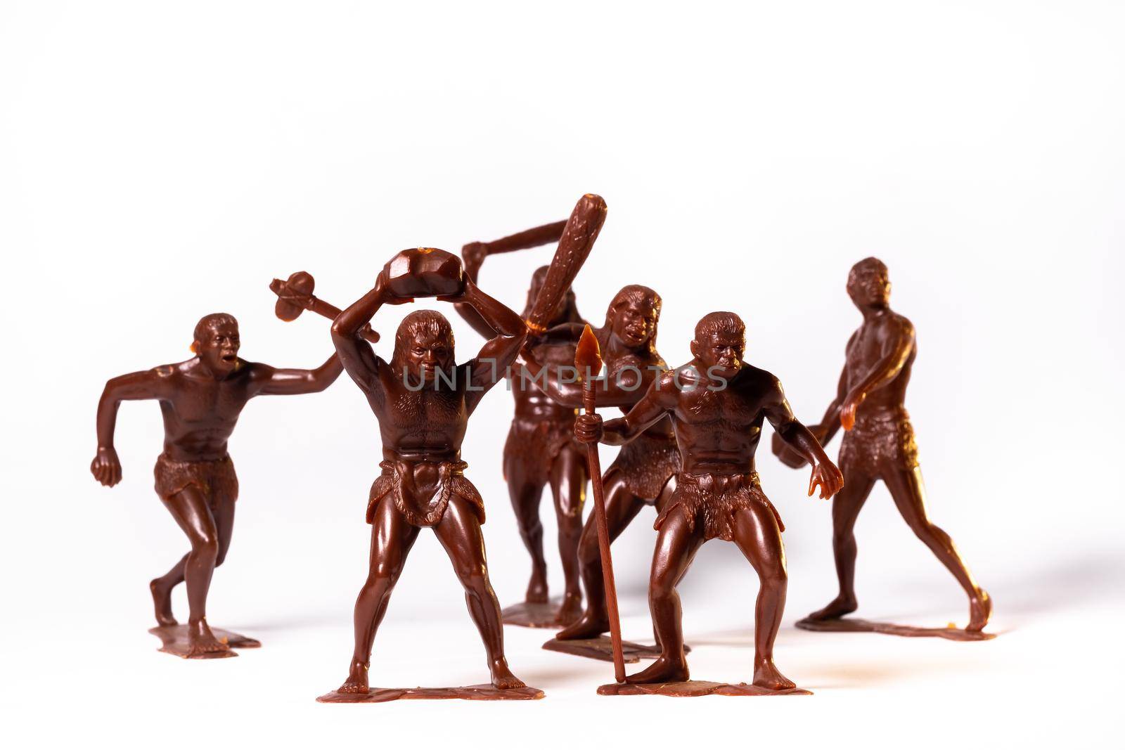 Large toy figures of primitive people on a white background.