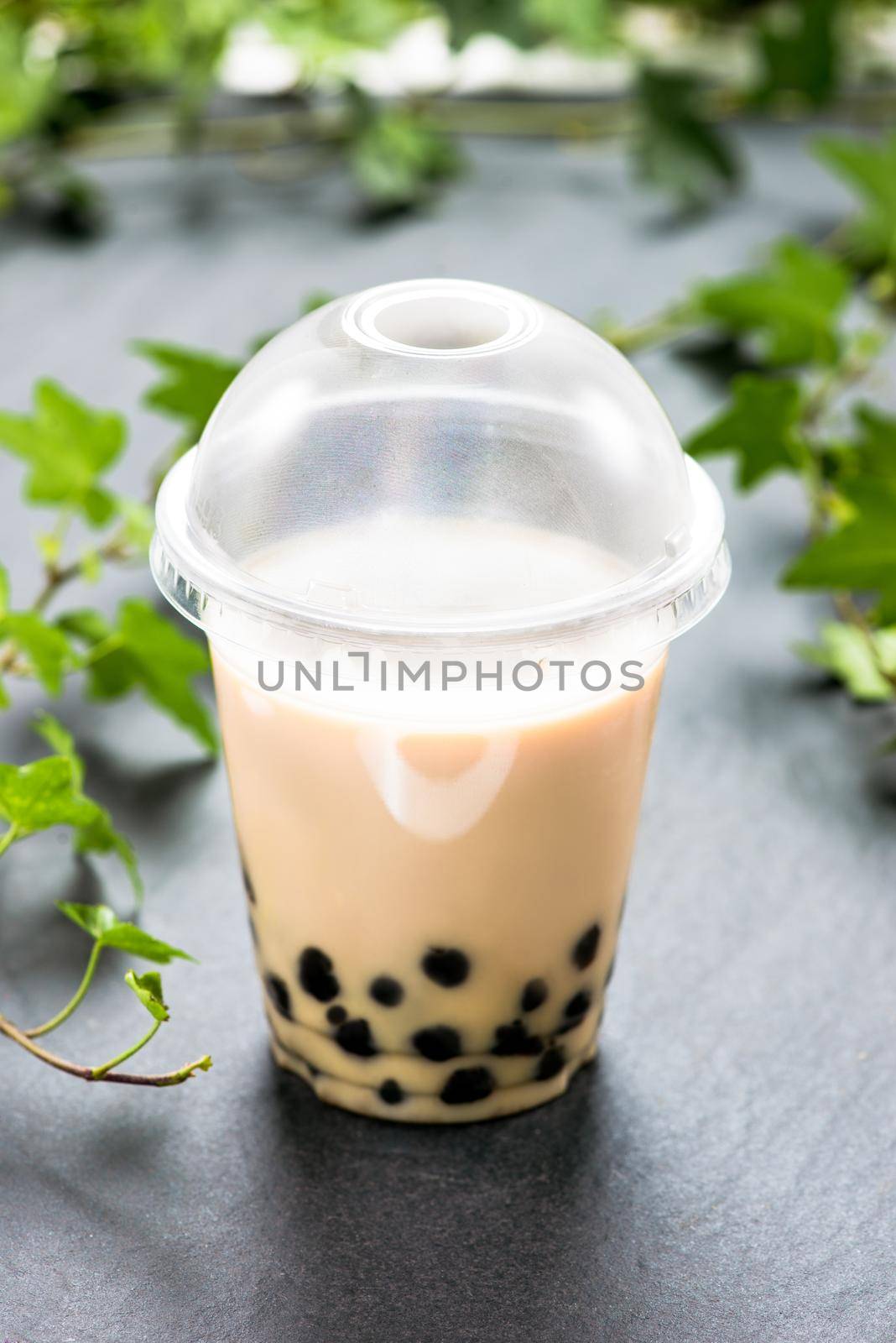 Bubble boba tea with milk and tapioca pearls in plastic cup by makidotvn