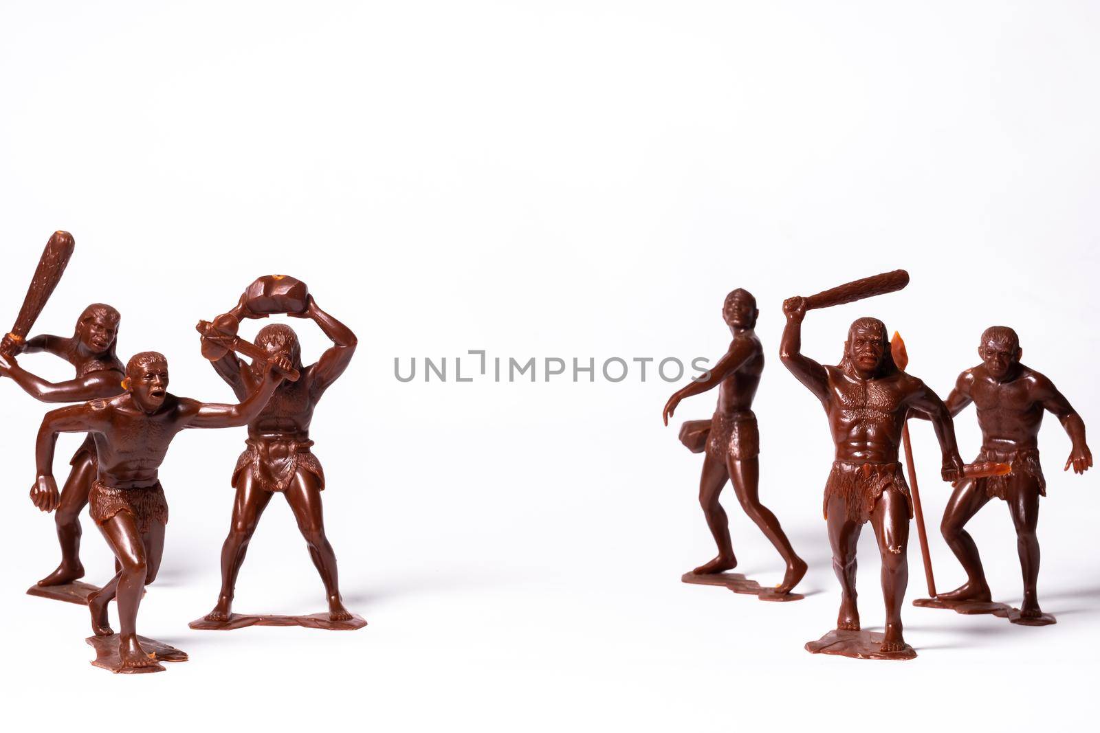 Large toy figures of primitive people on a white background.