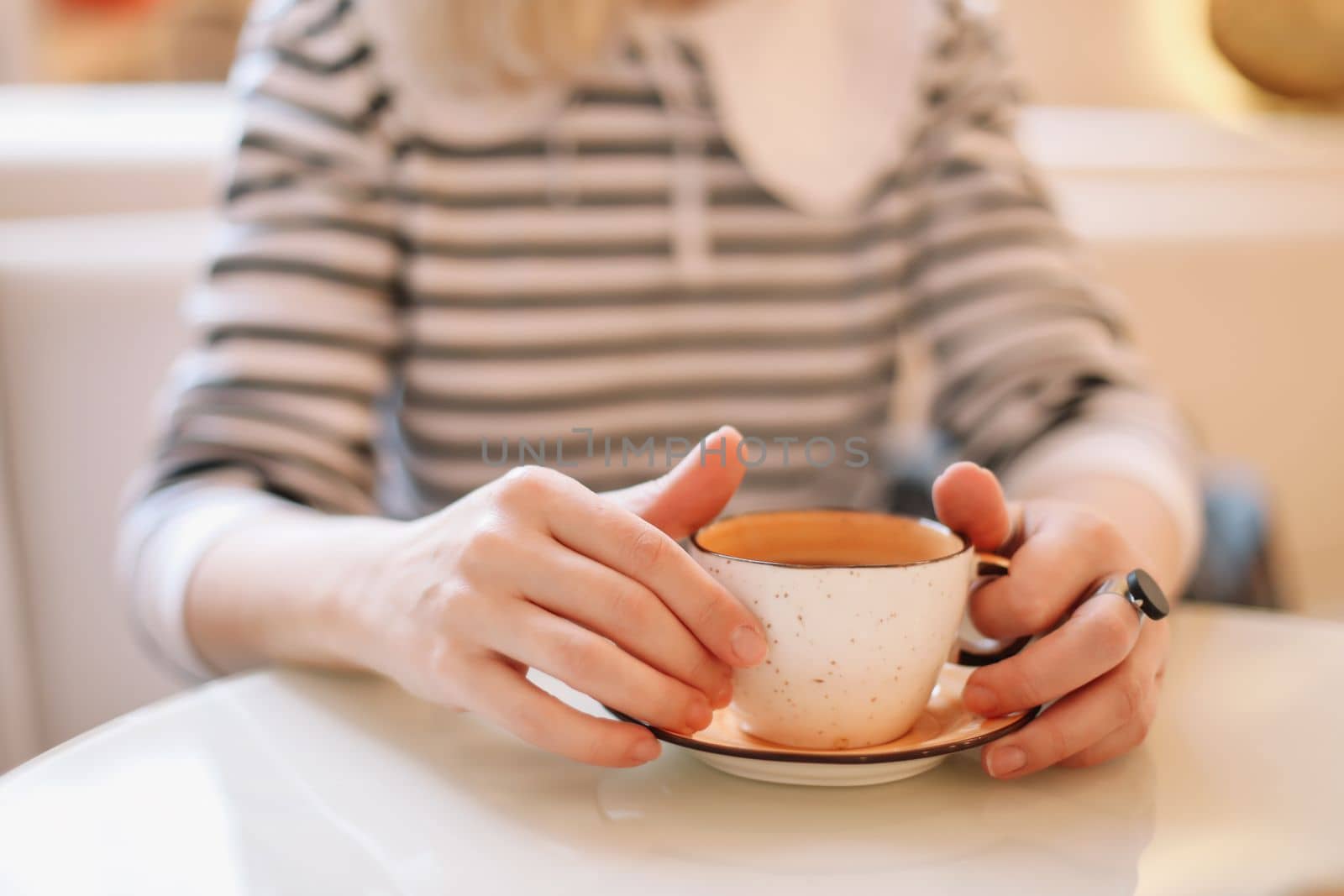 Woman's hands holding cup of hot drink coffee indoors. Still life composition.