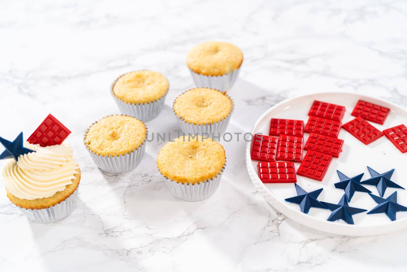 Decorating lemon cupcakes with patriotic blue chocolate star and red mini chocolate.