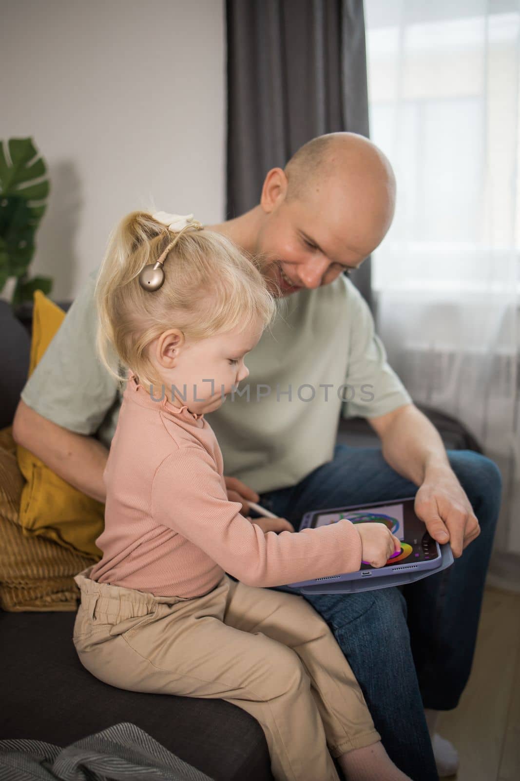 Deaf child girl with cochlear implant studying to hear sounds - recovery after cochlear Implant surgery and rehabilitation