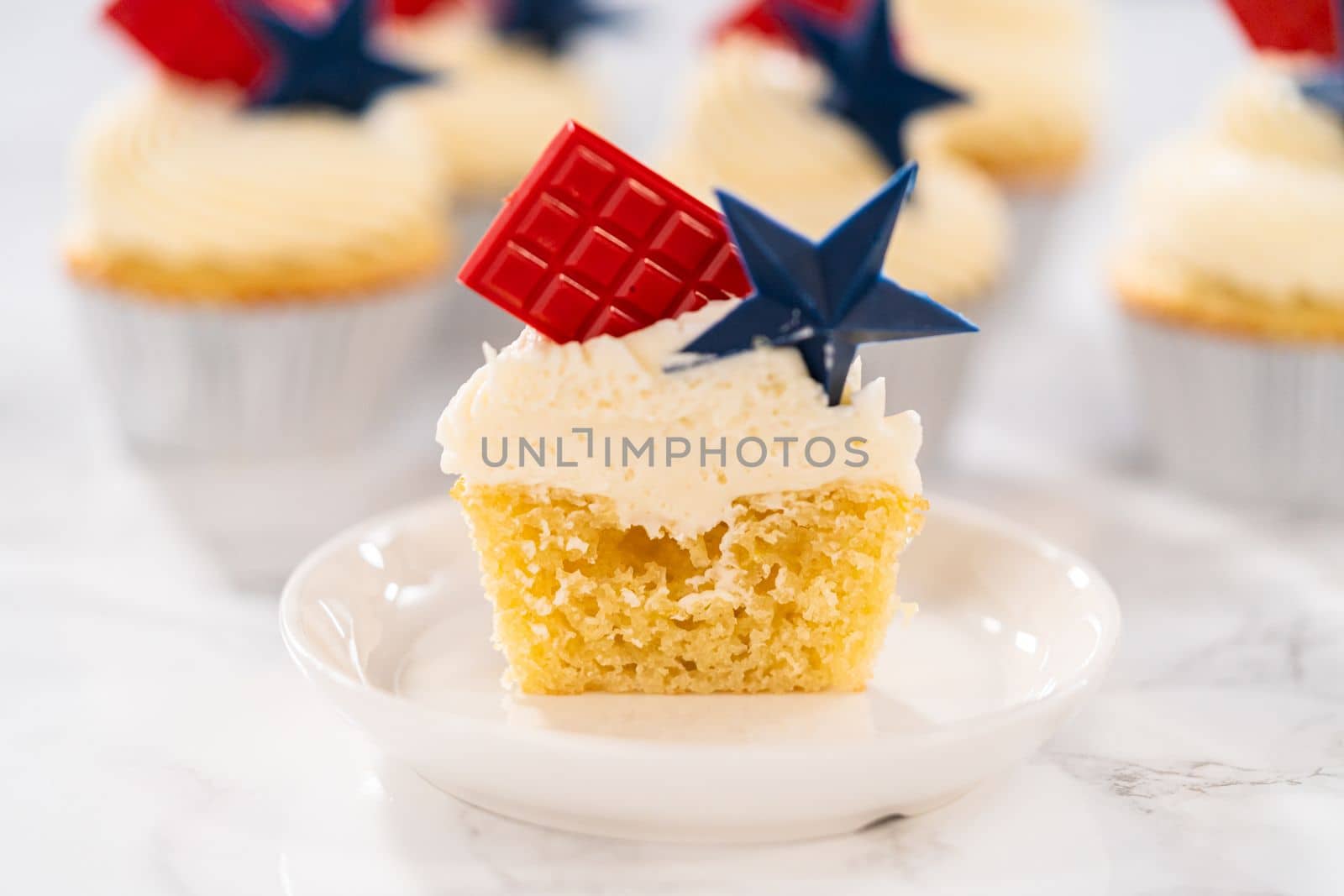 Sliced lemon cupcakes with lemon buttercream frosting, and decorated with patriotic blue chocolate star and red mini chocolate.