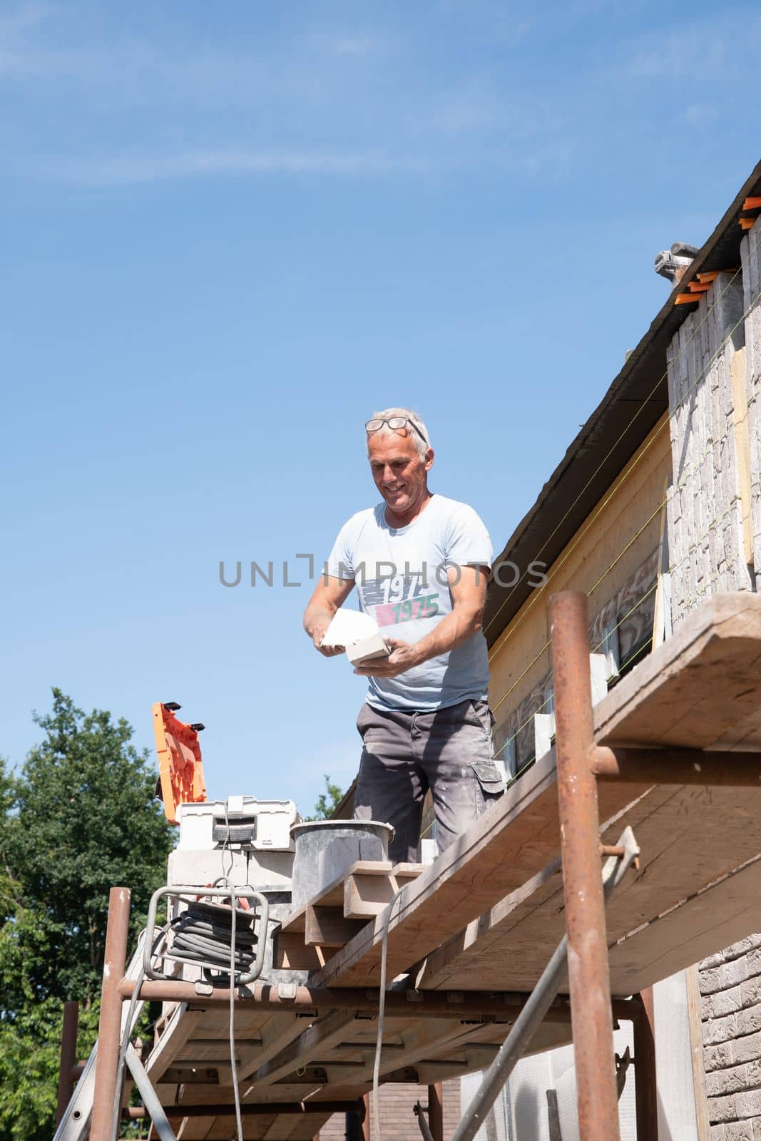 the bricklayer makes the facade of the house from gray bricks with cement and plaster at the construction site. High quality photo