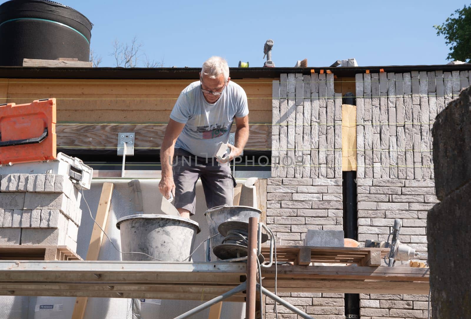 the bricklayer makes the facade of the house from gray bricks with cement and plaster at the construction site. High quality photo