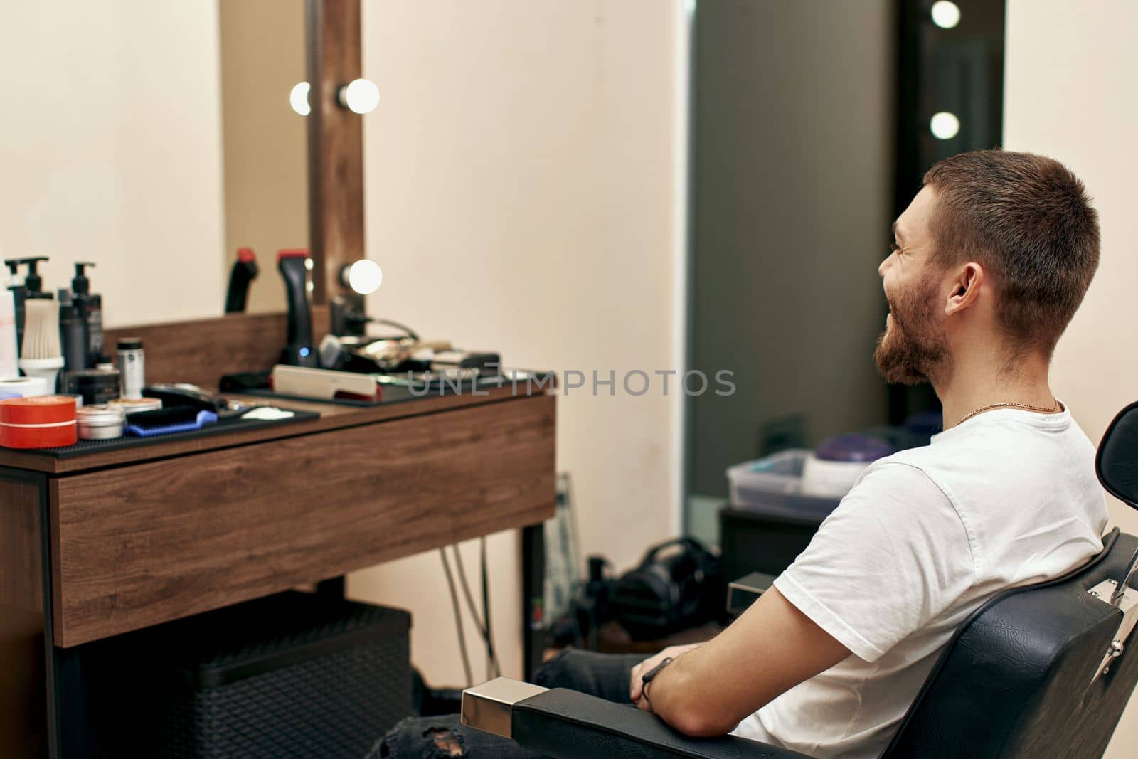 male bearded client in chair before haircut in barber shop