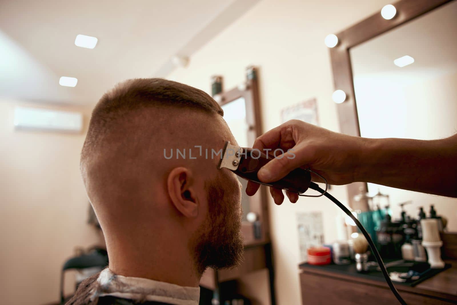Barber shaving handsome bearded man in barber shop.