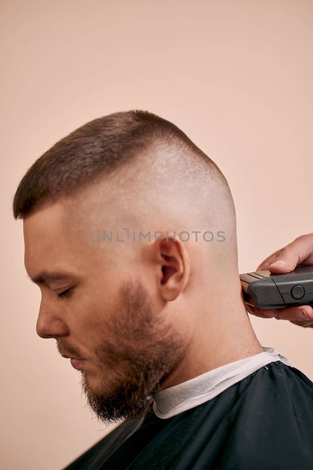 Barber shaving handsome bearded man in barber shop.