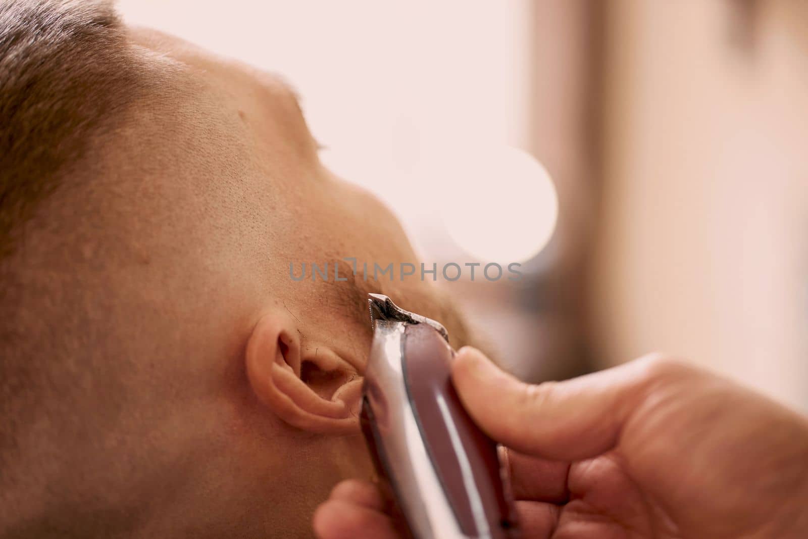 Barber shaving handsome bearded man in barber shop.