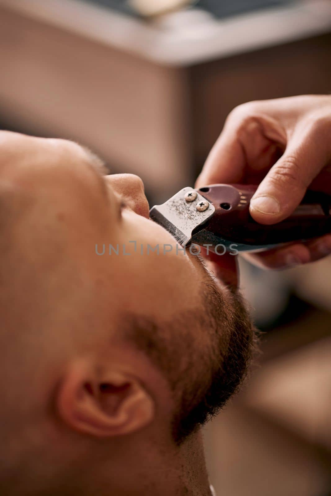 Barber shaving handsome bearded man in barber shop.