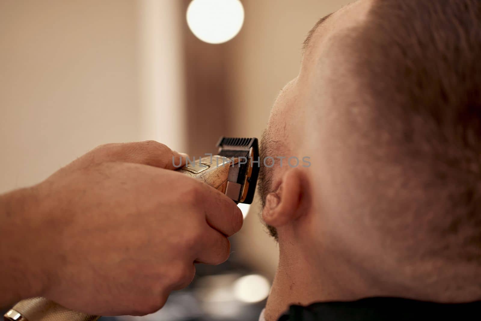 male hands of barber with hair clipper, close up.