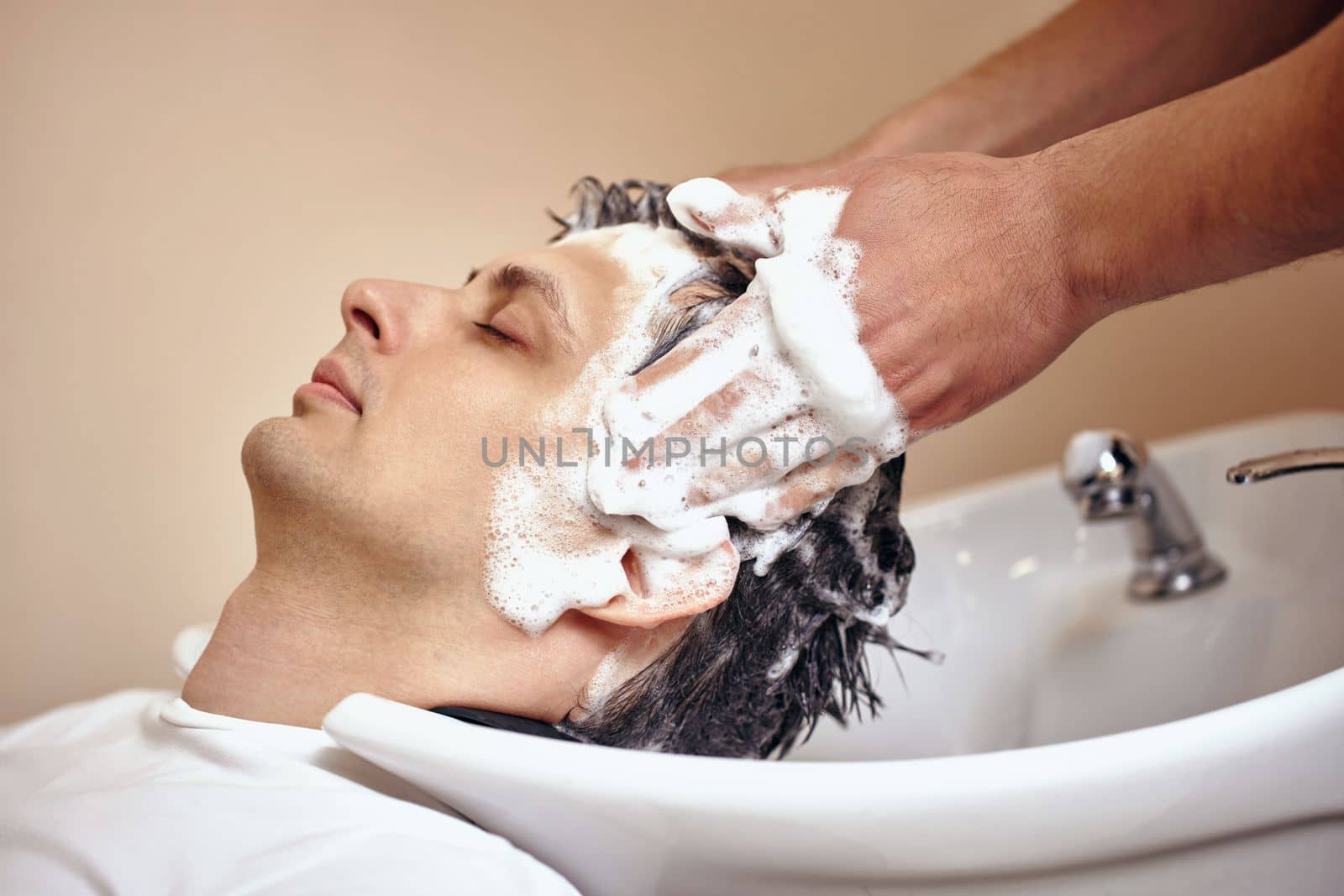 Barber washing hair of caucasian man in barber shop