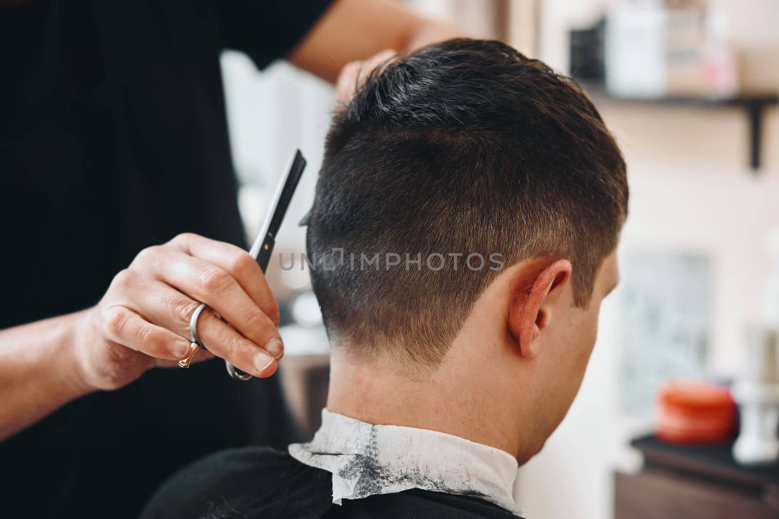 master hairdresser does hairstyle with scissors and comb.