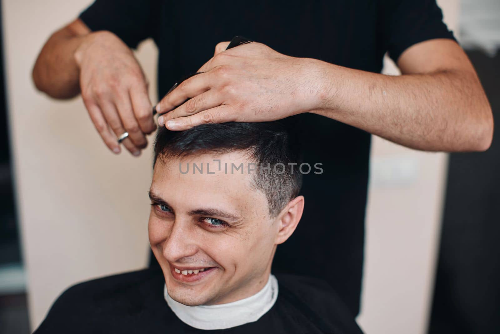 hairdresser does haircut for caucasian man in barber shop