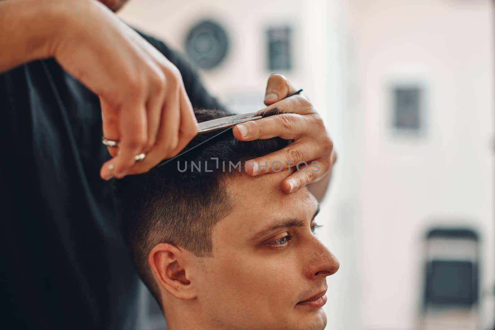 hairdresser does haircut for caucasian man in barber shop. close-up