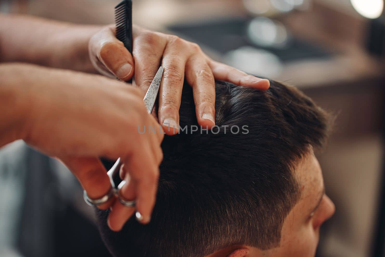 hairdresser does haircut for caucasian man in barber shop. close-up