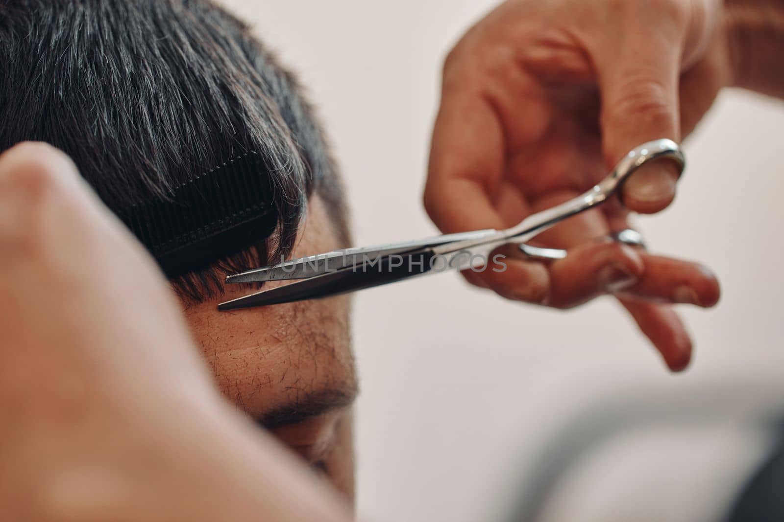 hairdresser does haircut for caucasian man in barber shop. close-up