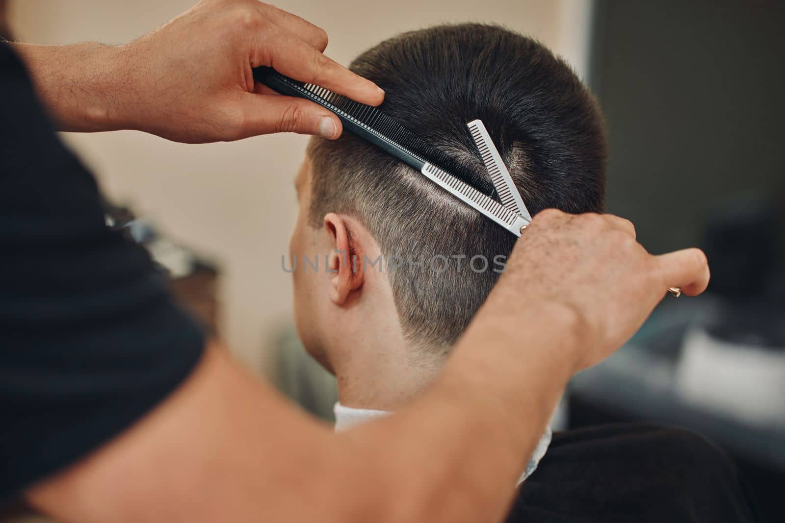 hairdresser does haircut for caucasian man in barber shop. close-up